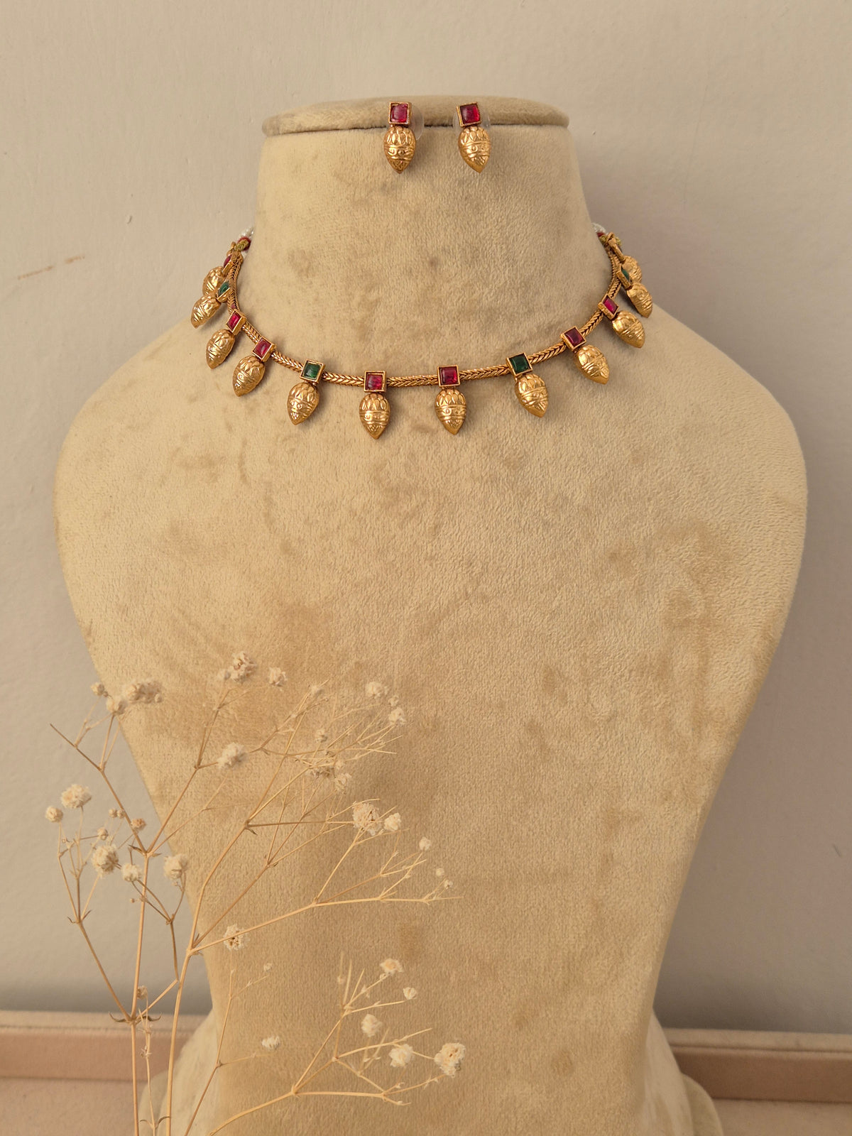 Gold-toned necklace and matching earrings with small green-red rectangular stones, by naitri.in