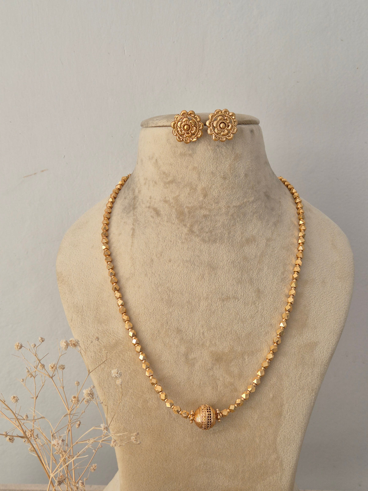 Nikki gold-toned beaded chain necklace set featuring intricate geometric beadwork and matching floral stud earrings displayed on a mannequin by Naitri.in