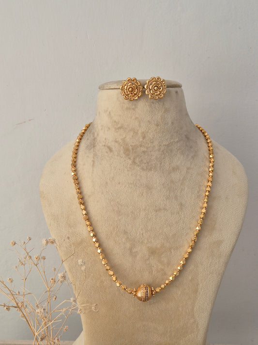 Nikki gold-toned beaded chain necklace set featuring intricate geometric beadwork and matching floral stud earrings displayed on a mannequin by Naitri.in