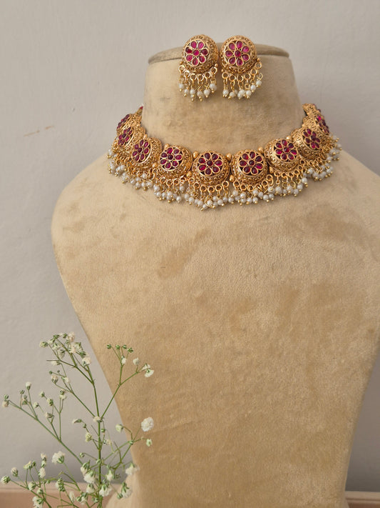 Gold necklace with red gemstones stone in the middle of the flower many golden beads hanging down by naitri.in