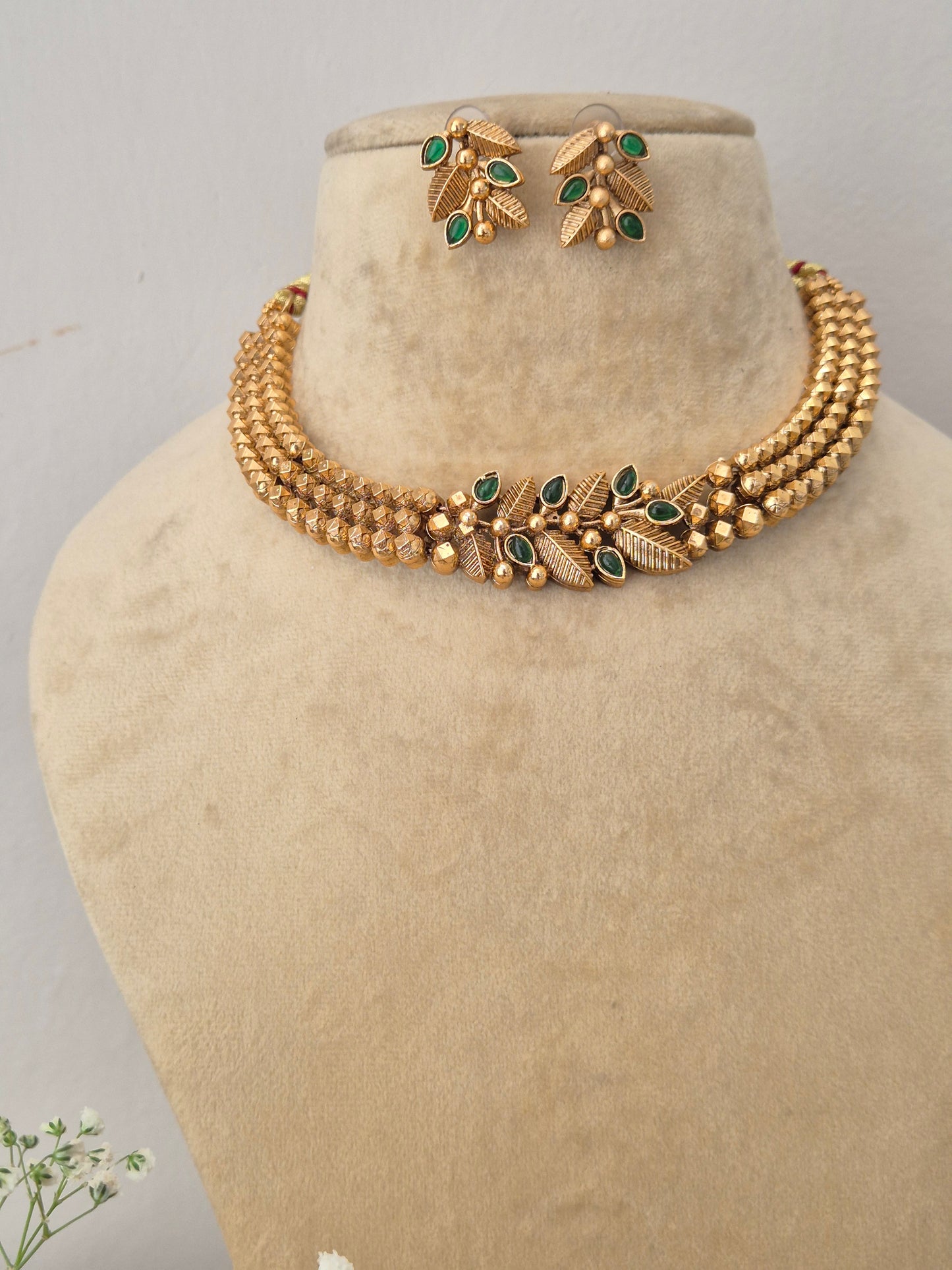Elegant gold-toned ethnic choker jewelry set with intricate green stone embellishments, by naitri.in