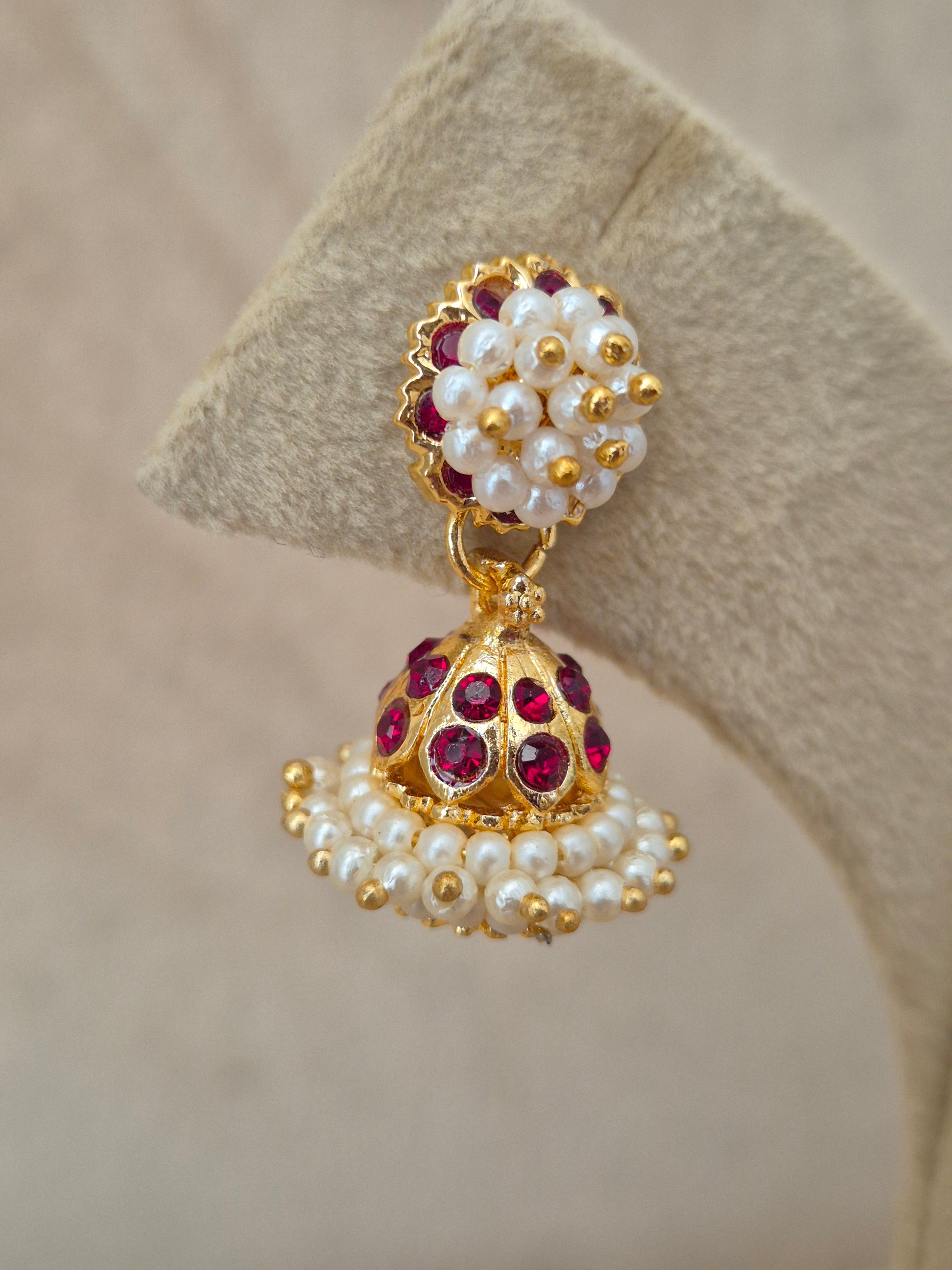 Traditional gold-toned festive earrings featuring an ornate dome drop with red gemstone settings and clustered white pearls, by naitri.in