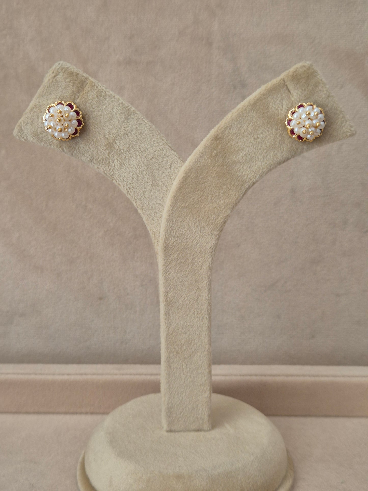 Gold-plated Niyati stud earrings with red stones and white pearl embellishments by naitri.in