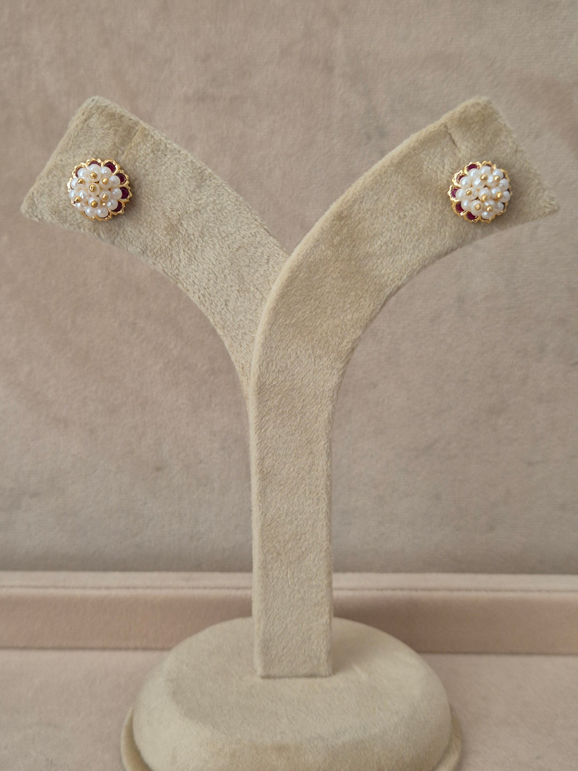 Gold-plated Niyati stud earrings with red stones and white pearl embellishments by naitri.in