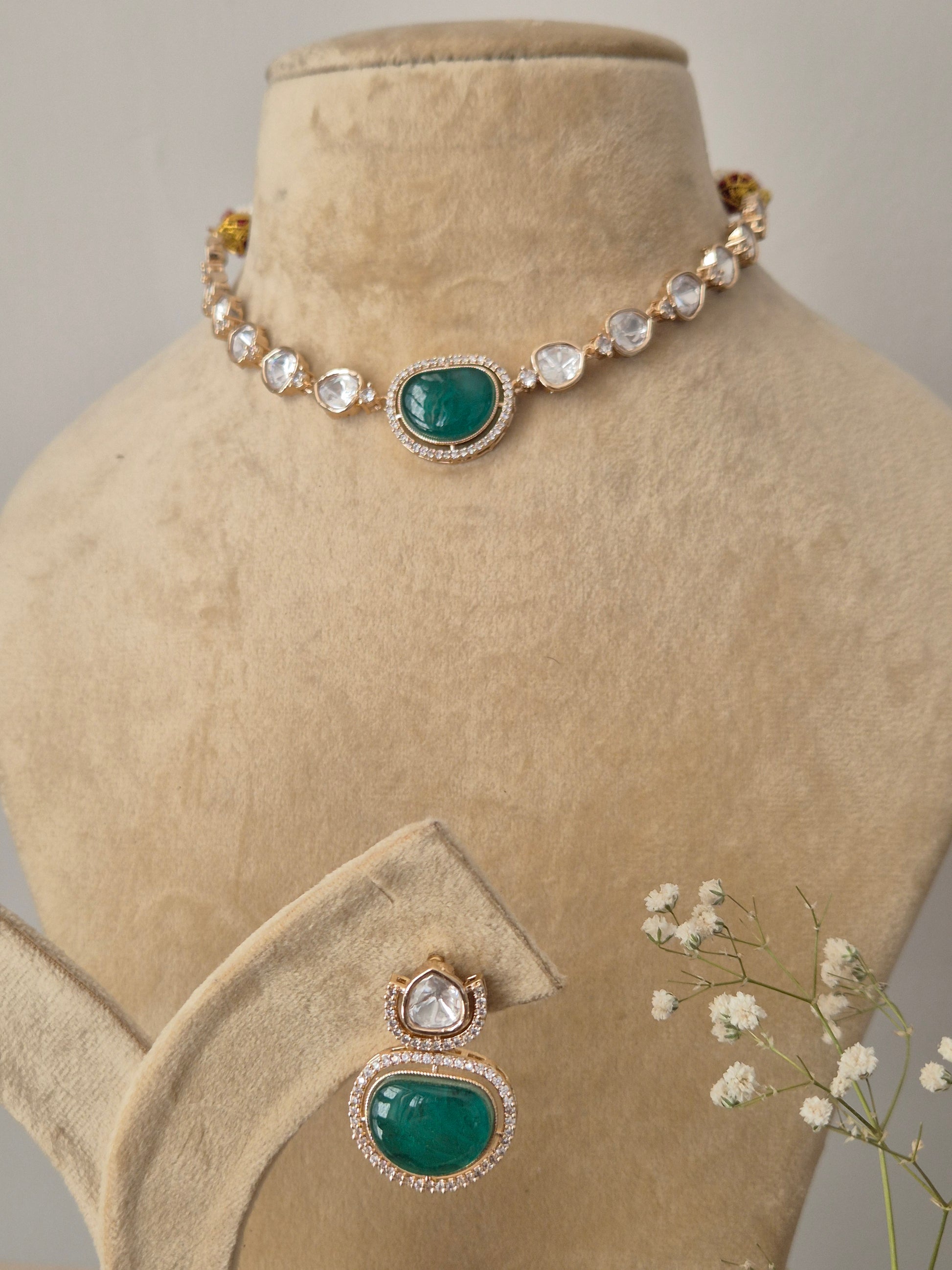 Close-up of a handcrafted necklace and earring set featuring emerald-colored stones and white AD crystals by naitri.in