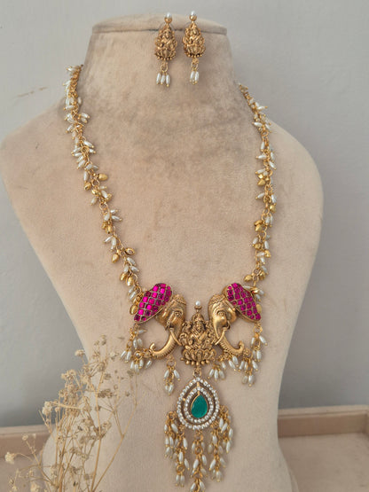 Nonika Necklace Set with Elephant Motif and Green Stone Pendant | Naitri Jewellery, Traditional gold temple necklace with pink and green stones and matching earrings by naitri.in