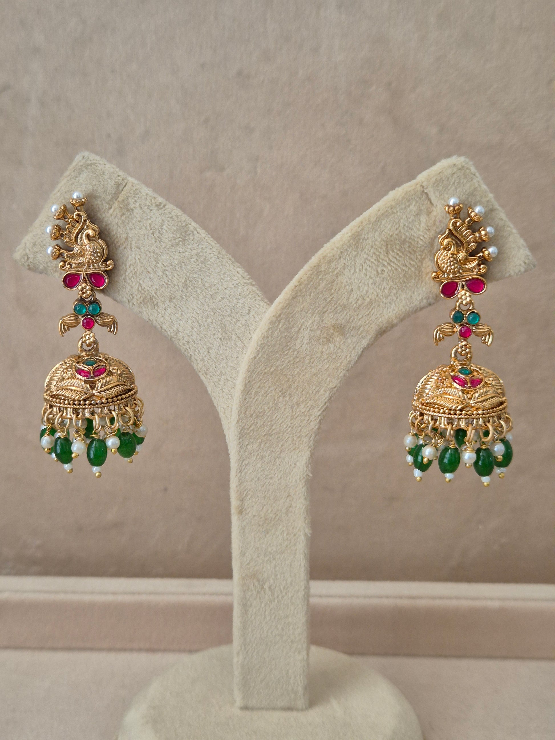 Traditional gold-toned peacock design Jhumka earrings with red and green gemstones and dangling green beads by naitri.in