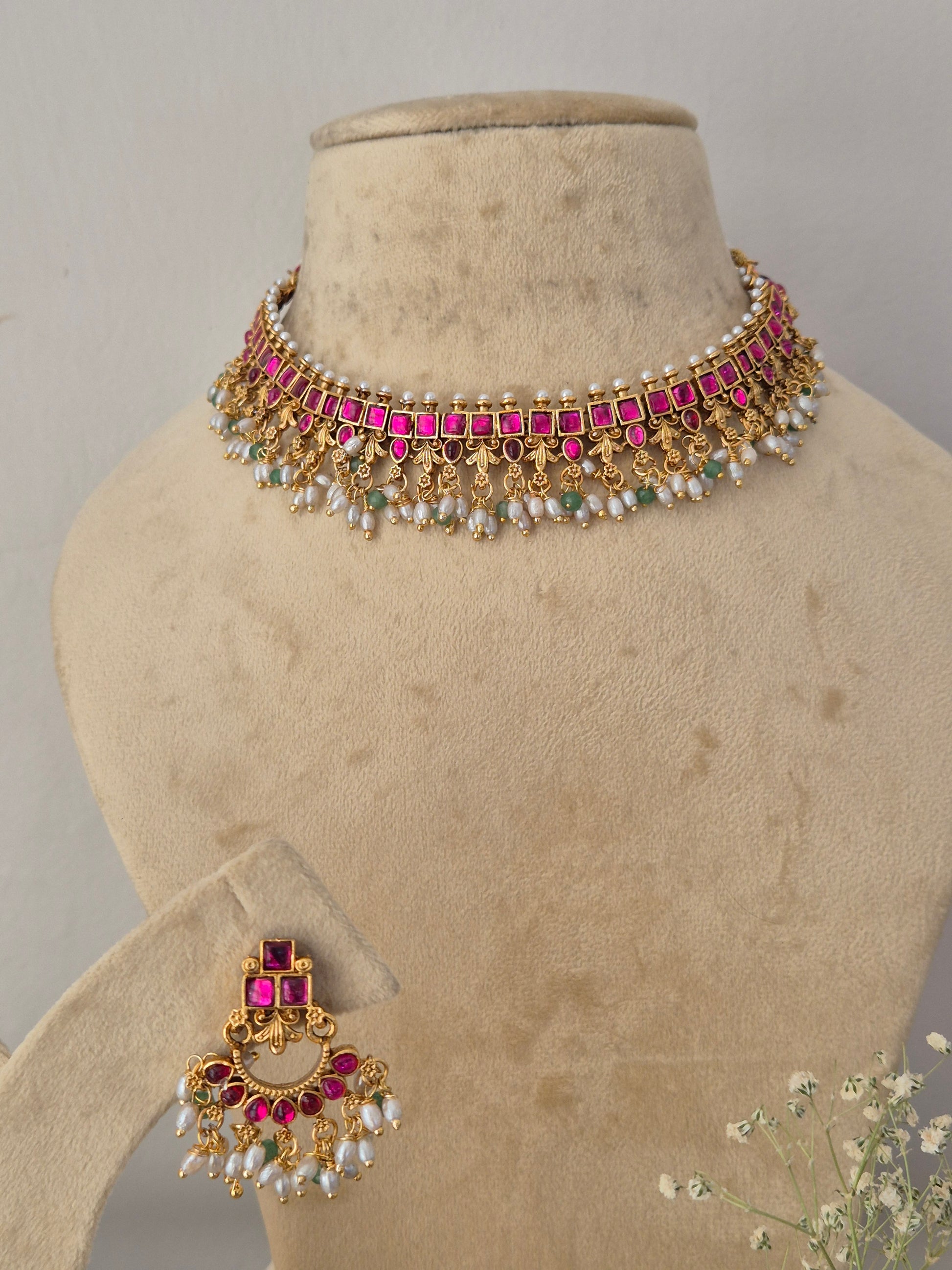 Gold-plated jewelry set featuring a choker necklace and matching earrings adorned with pink stones and white faux pearls, by naitri.in