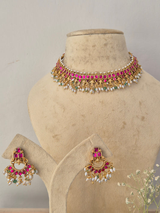 Gold-plated Indian jewelry set featuring a choker necklace and matching earrings, embellished with pink stones, white pearls, and green stones, by naitri.in