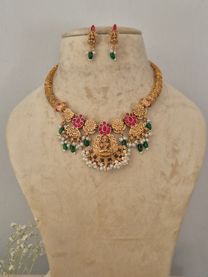 Traditional Indian gold-toned choker necklace set with detailed temple motifs, red and green stone embellishments, and hanging white pearl beads by naitri.in