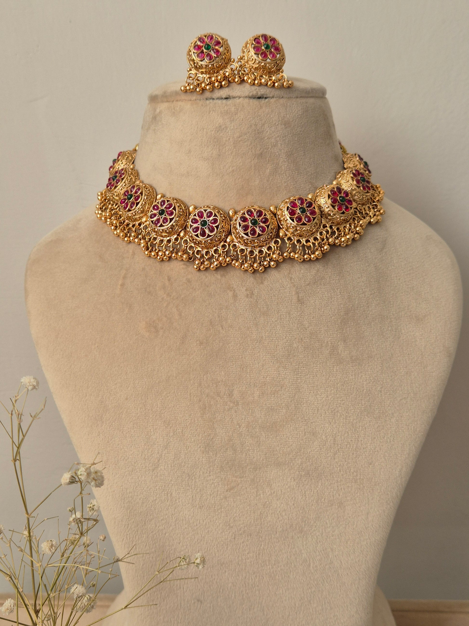 Floral gold necklace adorned with side design like bunches and green red studded flower charms by naitri.in