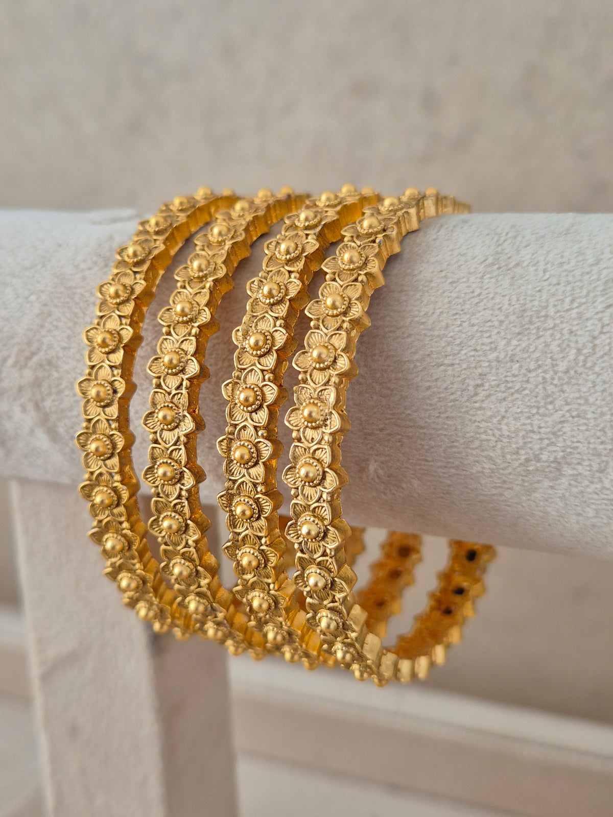 Set of four traditional floral textured gold-plated bangles by naitri.in