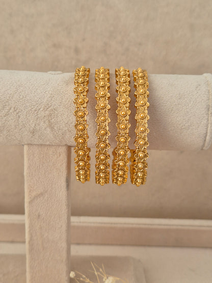  Set of 4 gold-plated Padma bangles featuring a repeated floral motif pattern by naitri.in