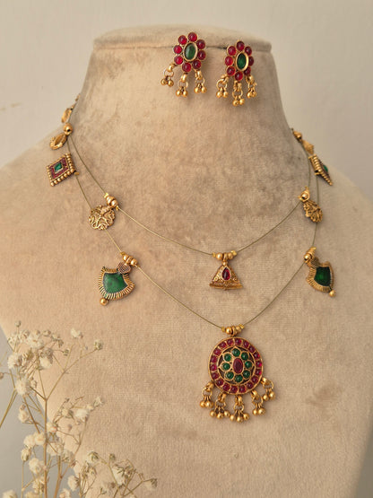 Handcrafted Palki necklace set with red and green gemstone accents and gold-plated floral motifs by naitri.in