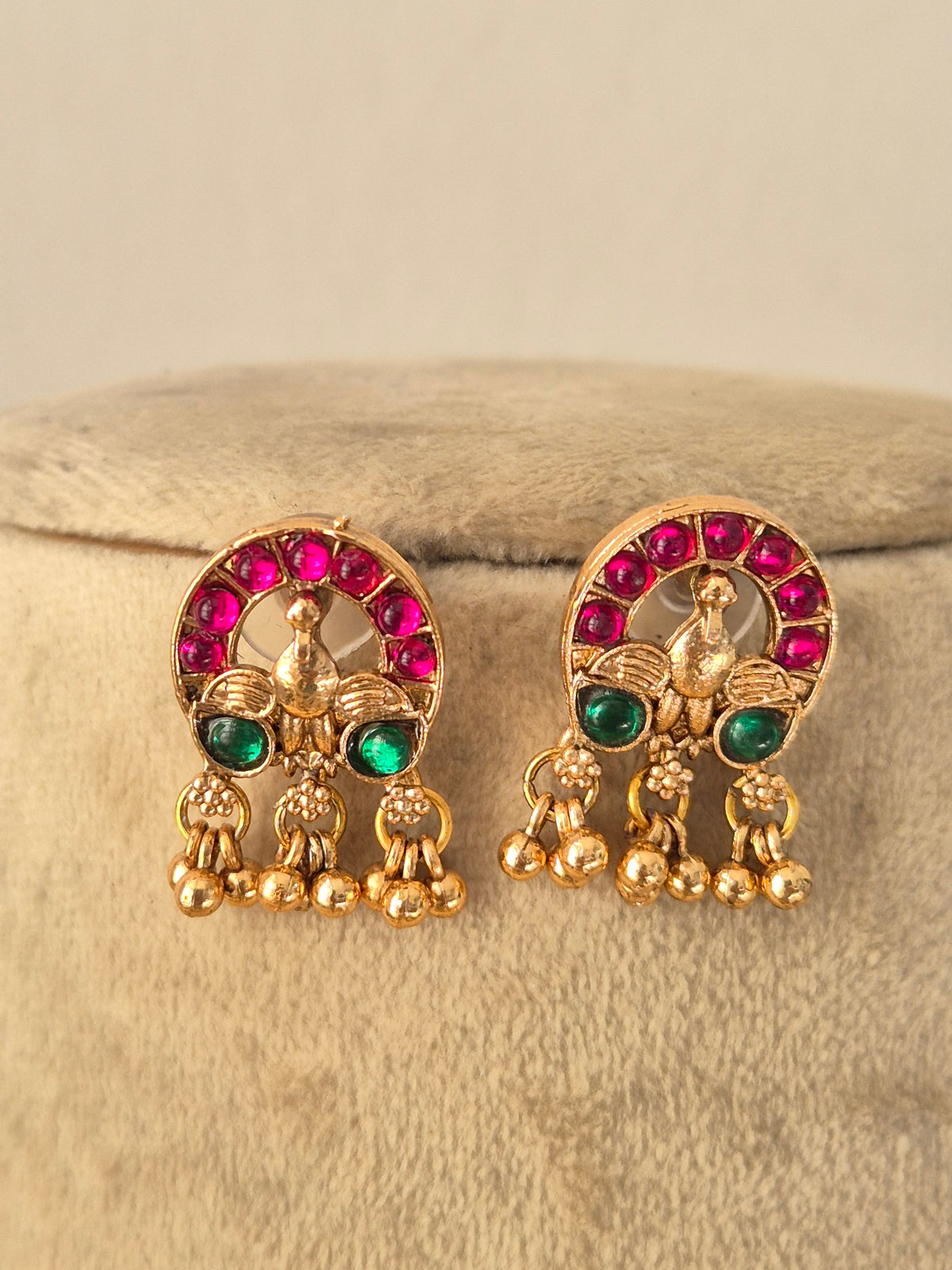 Ornate gold-toned ethnic necklace with ruby and emerald-colored stones, paired with matching stud earrings by naitri.in