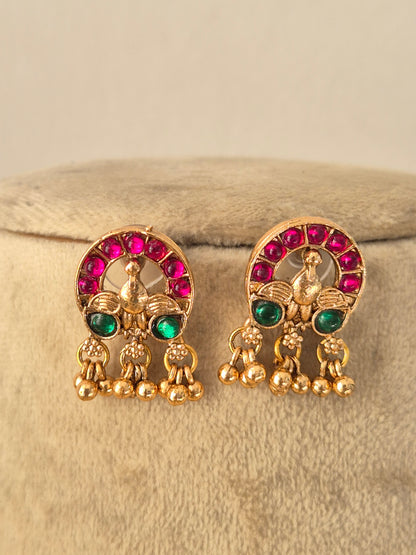 Ornate gold-toned ethnic necklace with ruby and emerald-colored stones, paired with matching stud earrings by naitri.in