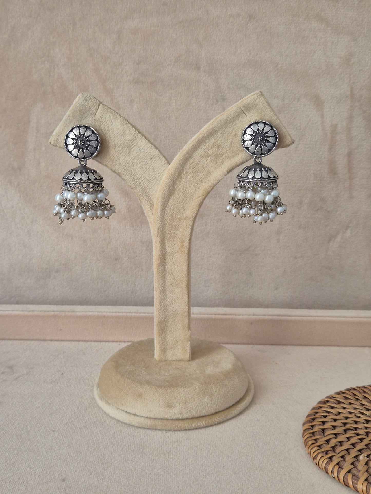 Pair of silver-toned jhumka earrings featuring a wheel-patterned floral stud and white pearl dangles by naitri.in