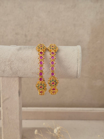 Set of 2 gold-plated bangles studded with ruby red stones, emerald green accents, by naitri.in 
