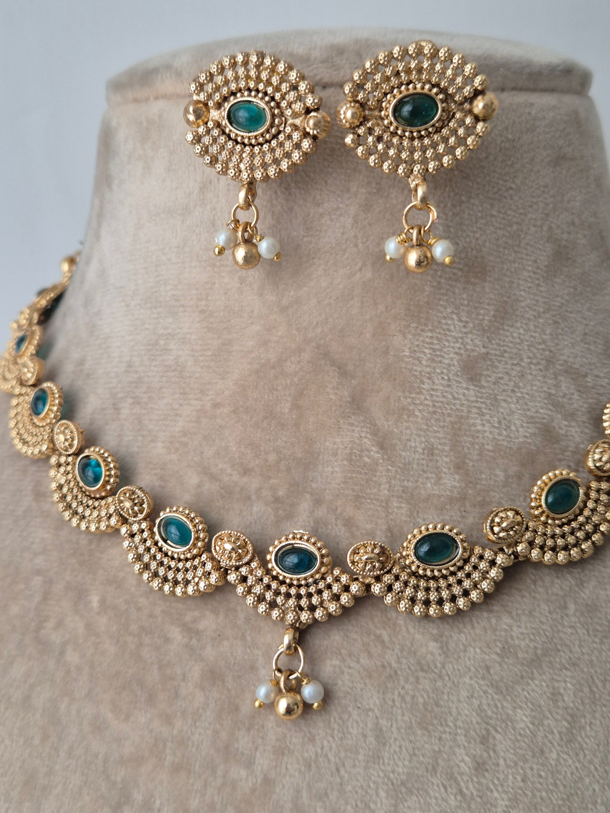 Golden necklace with earring and green stones in the necklace for wedding and events which enhances your beauty by naitri.in