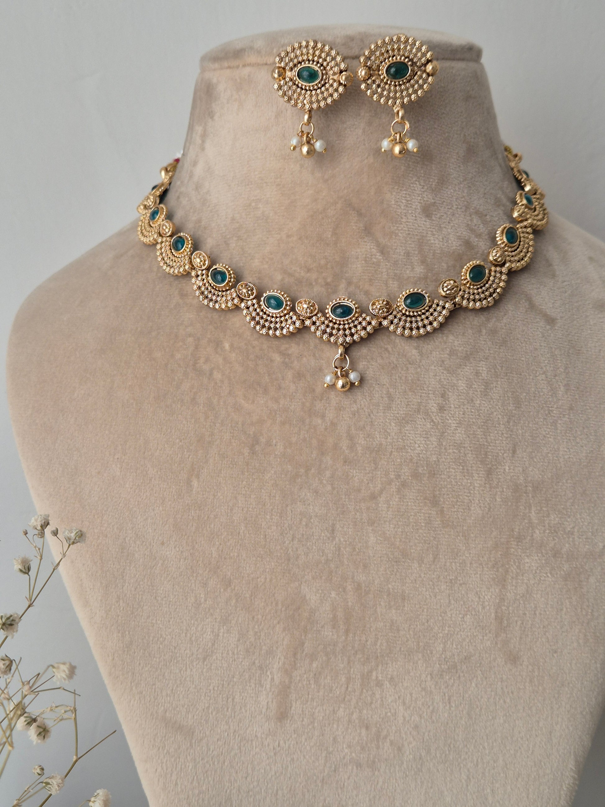 Semi sphere design with green stone in middle and golden and white pearls dropping  down from middle of necklace by naitri.in