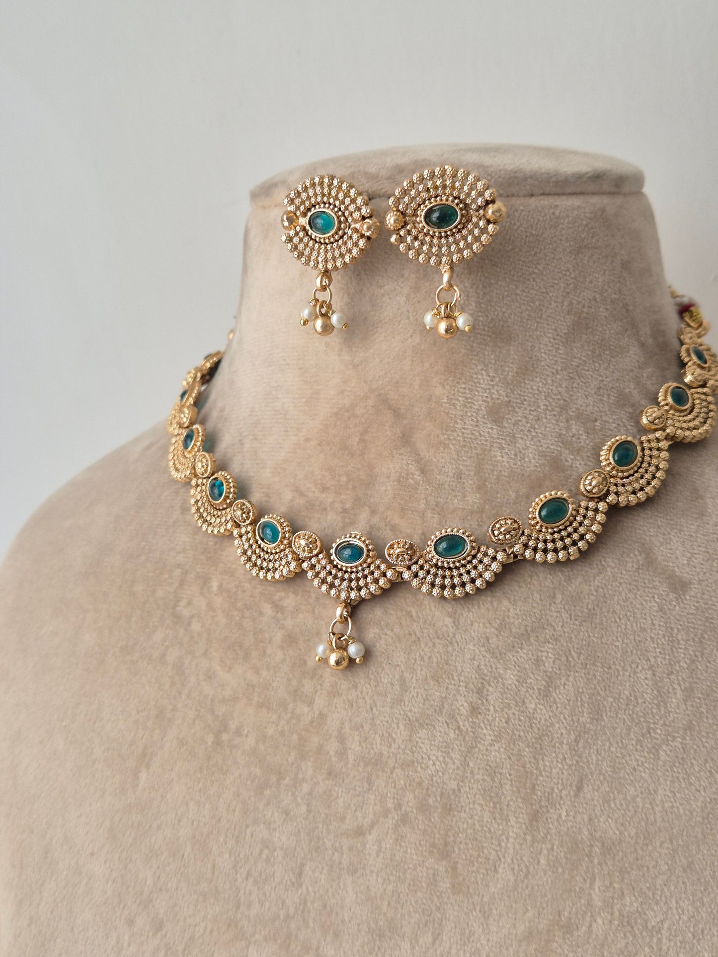 Gold necklace with green stones necklace with same designed earring with green stones by naitri.in