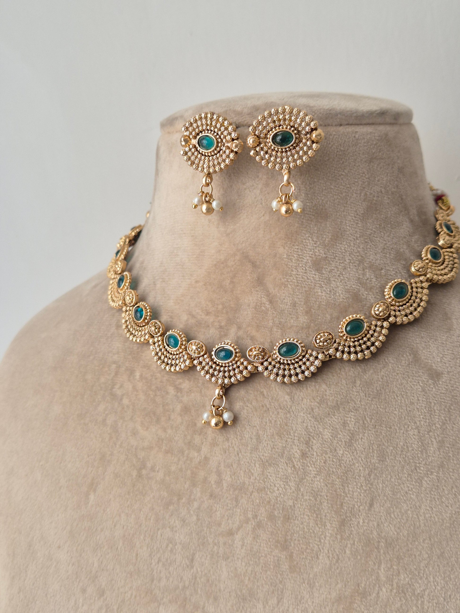 Gold necklace with green stones necklace with same designed earring with green stones by naitri.in