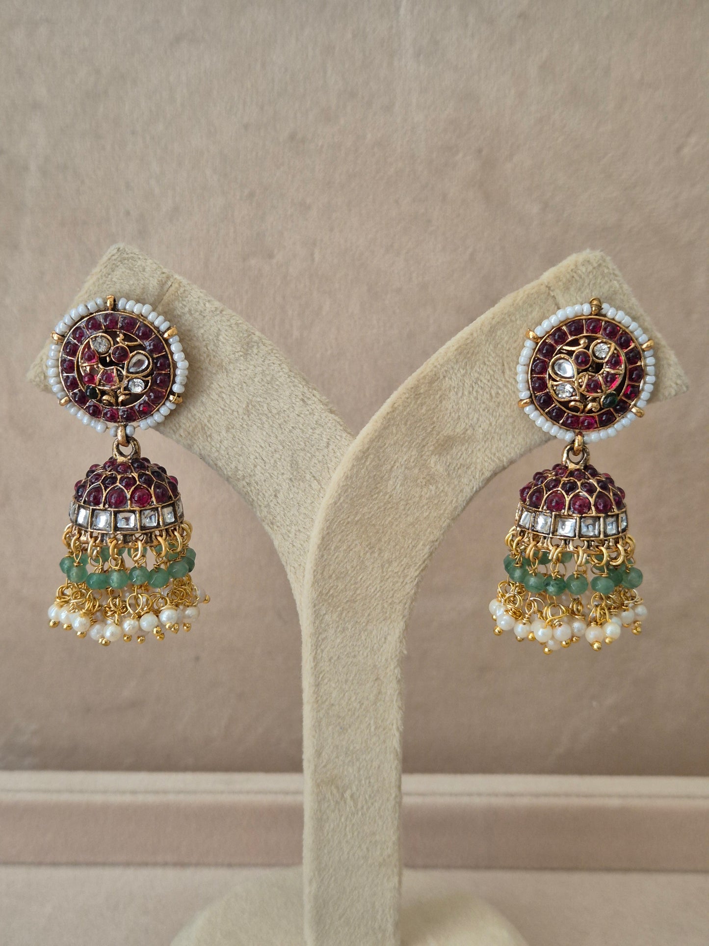 Traditional gold-toned festive Jhumka earrings with red and green gemstone accents and white seed pearls by naitri.in