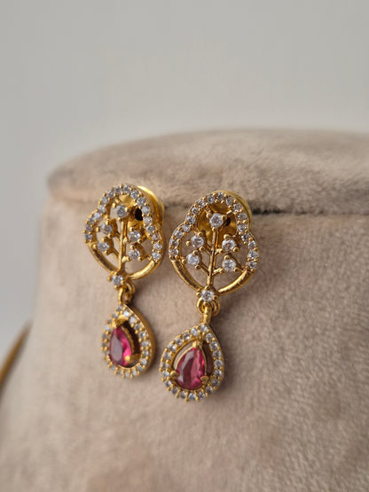 Golden leaf shaped earrings with pink gemstones and white stones attached beautifully by naitri.in