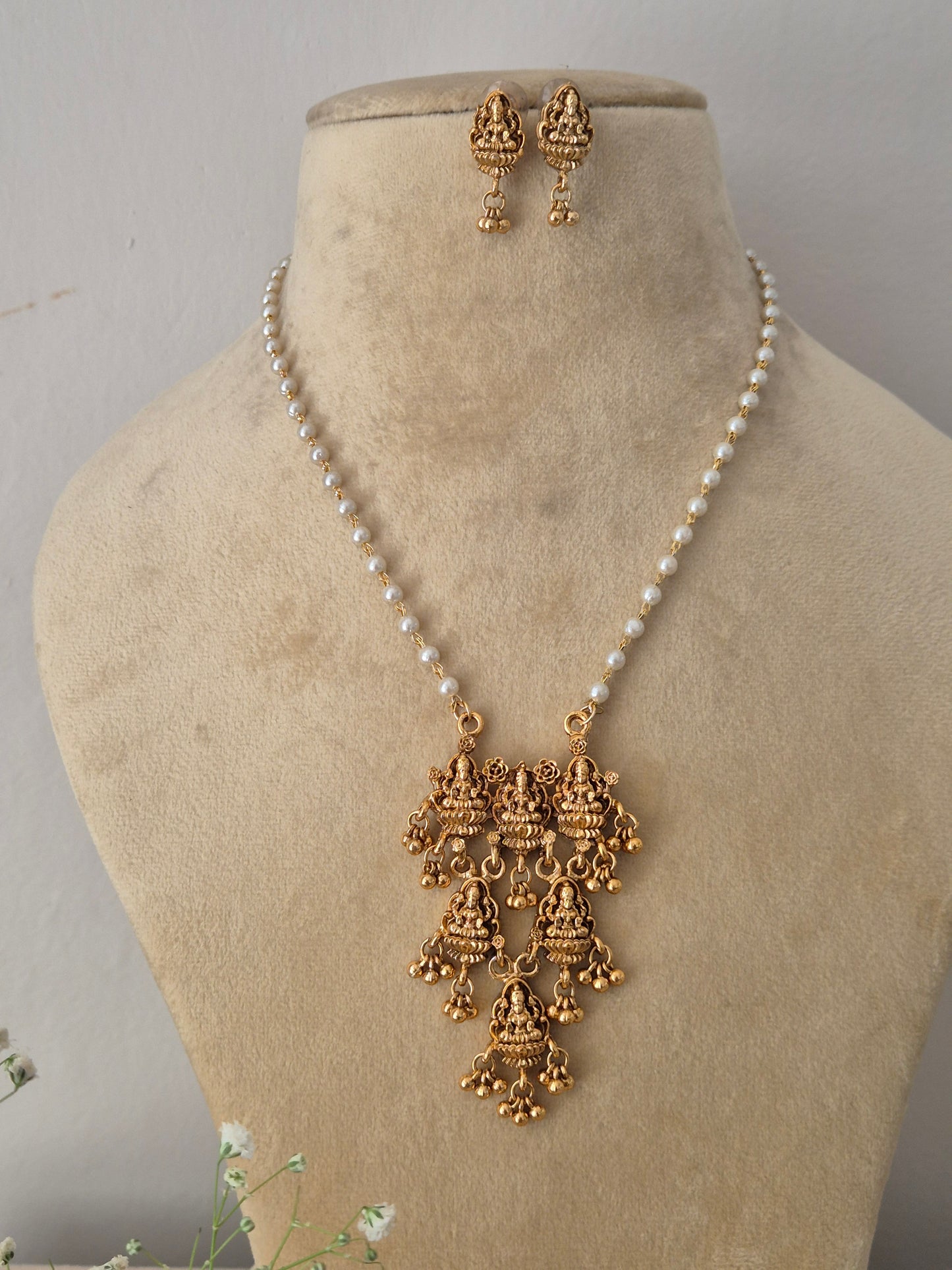 Gold-plated temple pendant necklace with a white pearl chain and matching hanging earring By naitri.in