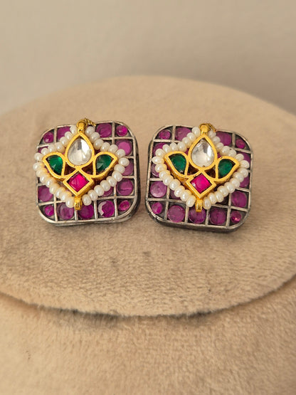 A pair of square gold-toned earrings with pink gemstones, white pearl-like borders, and green and white central motifs by naitri.in