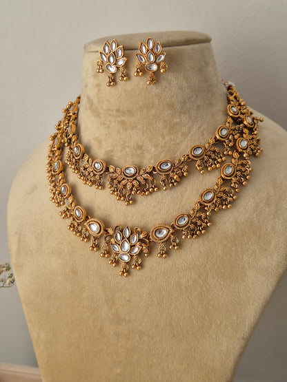 Qaynat Necklace Set: Gold-polished double-strand choker with white stone embellishments and matching drop earrings from the Golden Ethnic Jewellery line by naitri.in