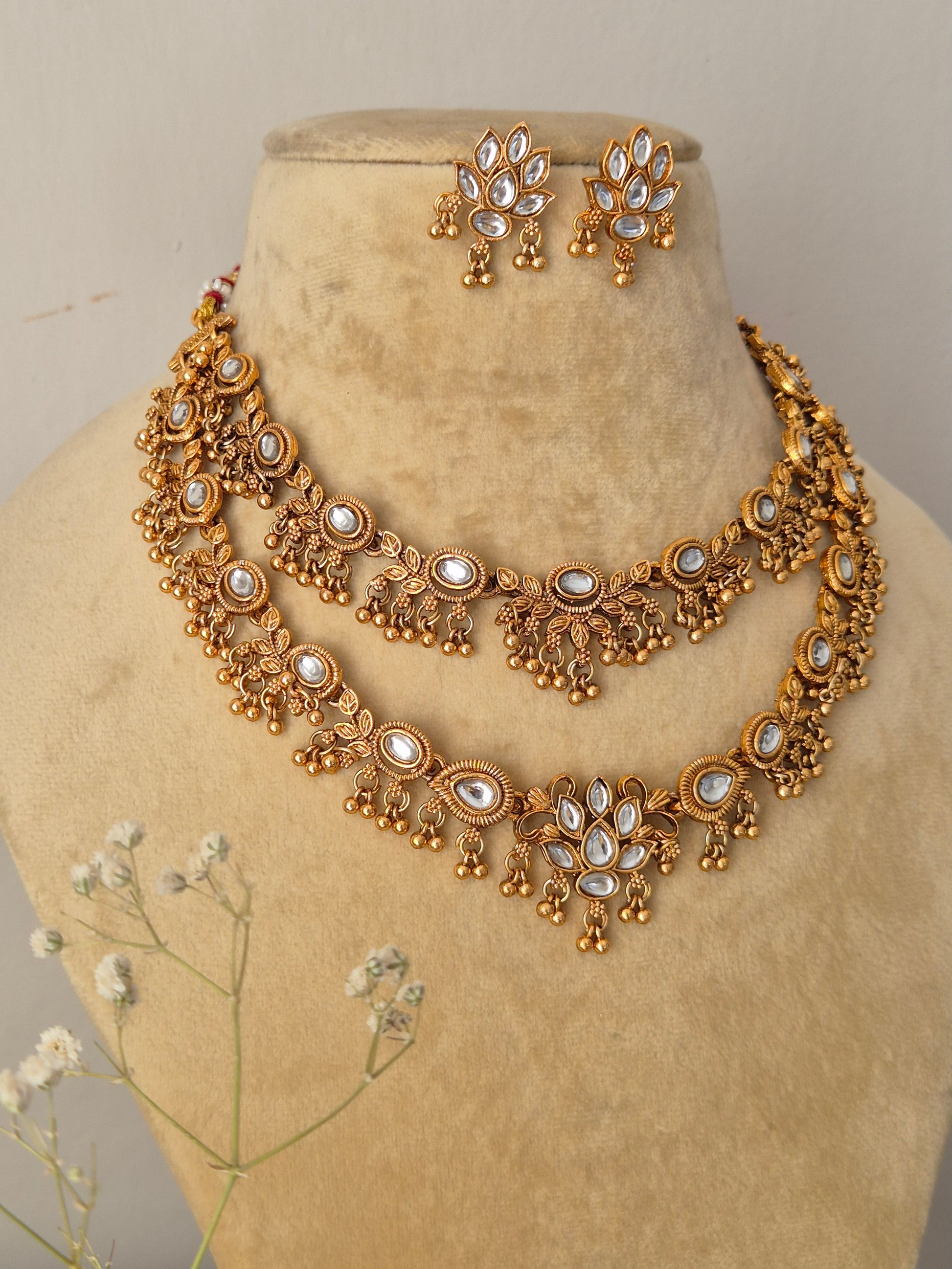 Handcrafted double-layered gold choker necklace and matching earrings featuring white floral stones by naitri.in