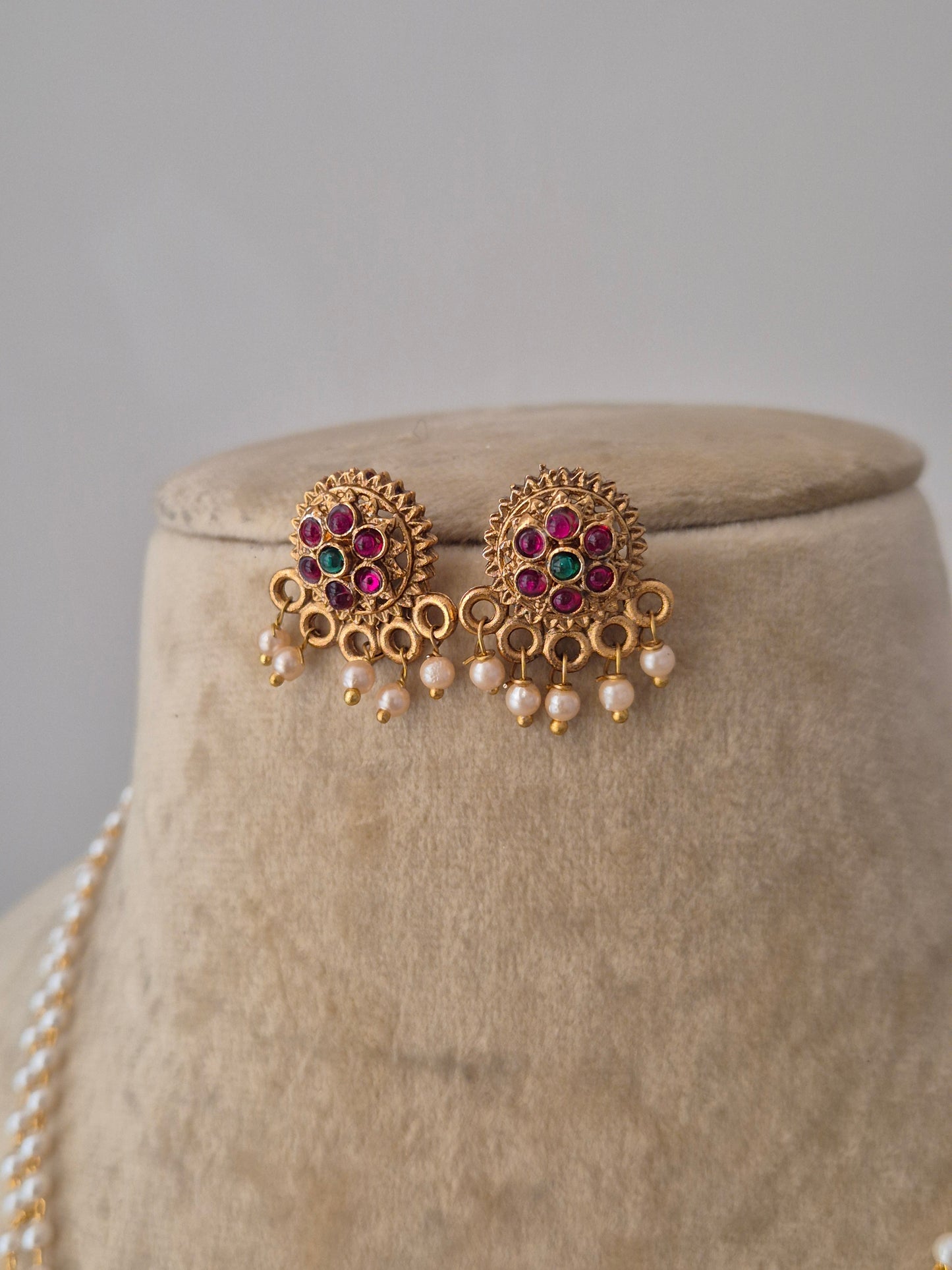 "Gold-plated ruby-pink and green stone embellishments, and white pearl drops earrings by naitri.in