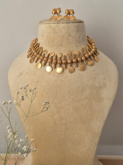 Handcrafted gold-polished brass choker necklace featuring alternating textured pyramid motifs and dangling round coin charms, with matching coin-drop stud earrings by naitri.in