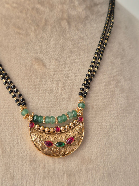 Handcrafted Rashi Mangalsutra Necklace featuring green and red gemstones on a traditional black bead chain with a polished golden pendant by naitri.in