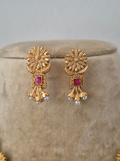 Antique gold earrings earrings and small red gemstones intricate textured circular engravings, small red stone embellishments, and delicate white hanging pearls by naitri.in