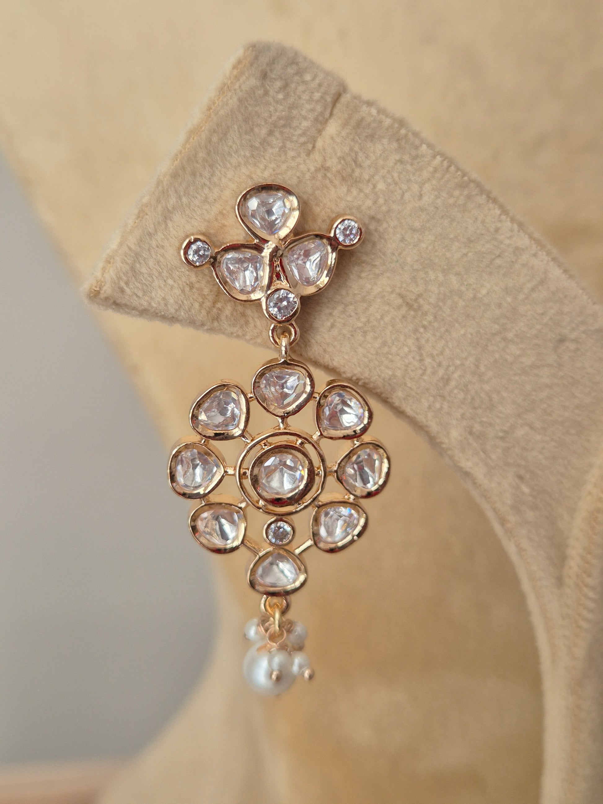 Close-up of a floral design American diamond necklace with teardrop pearl accents and a polished gold finish by naitri.in