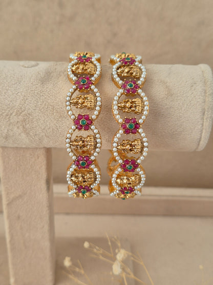 Set of two traditional stone and pearl studded gold-plated bangles by naitri.in