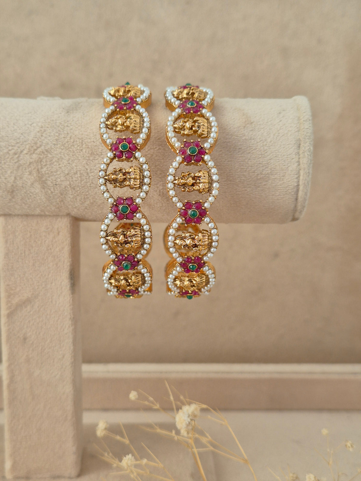 Set of 2 gold-plated bangles featuring oval-shaped motifs studded with green and pink gemstones surrounded by tiny white pearls by naitri.in