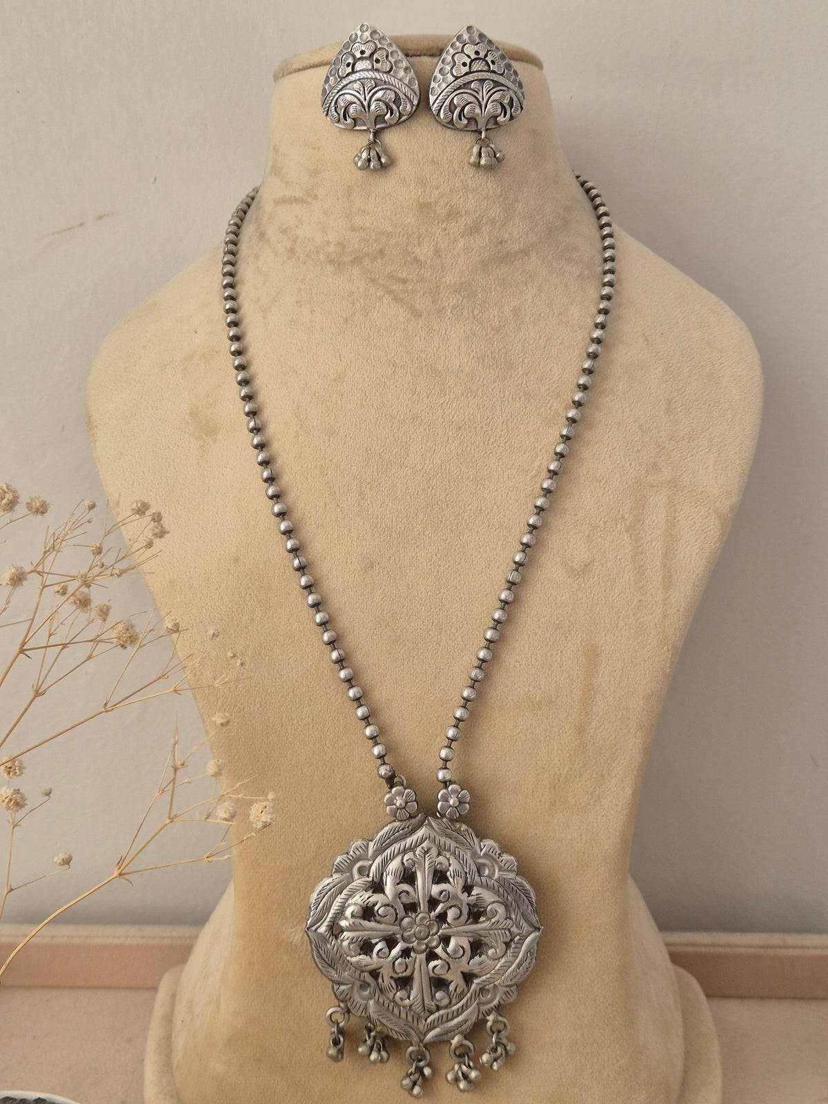 Oxidized silver long chain necklace with an ornate pendant and matching drop earrings by naitri.in
