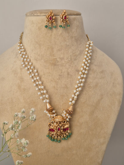 Handcrafted dual-strand pearl necklace featuring a detailed gold-tone brass alloy pendant with red and green stones and small emerald-colored bead drops by naitri.in