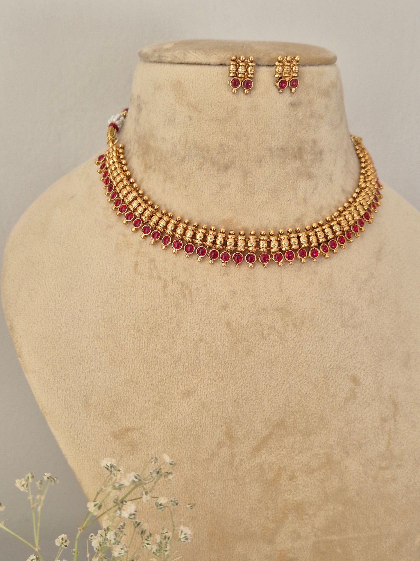 Gold-toned traditional Indian choker necklace and matching drop earrings with red stone accents, Necklace Set by Naitri featuring an ethnic gold-plated choker and matching traditional motif earrings with pink stones for festive wear,  by naitri.in