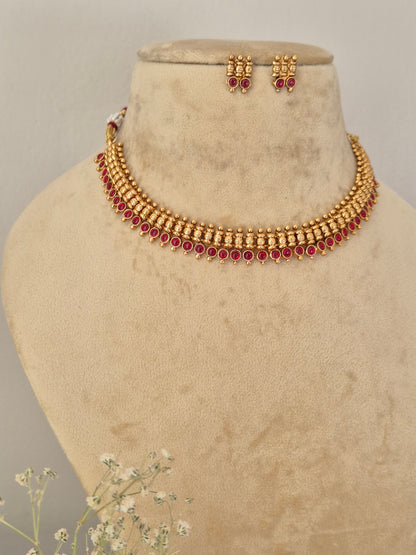 Gold-toned traditional Indian choker necklace and matching drop earrings with red stone accents, Necklace Set by Naitri featuring an ethnic gold-plated choker and matching traditional motif earrings with pink stones for festive wear,  by naitri.in