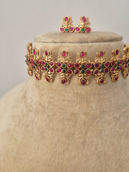 Gold-polished wide ethnic collar with red and green kemp stone embellishments and matching stud earrings from the Golden Ethnic Jewellery line by naitri.in