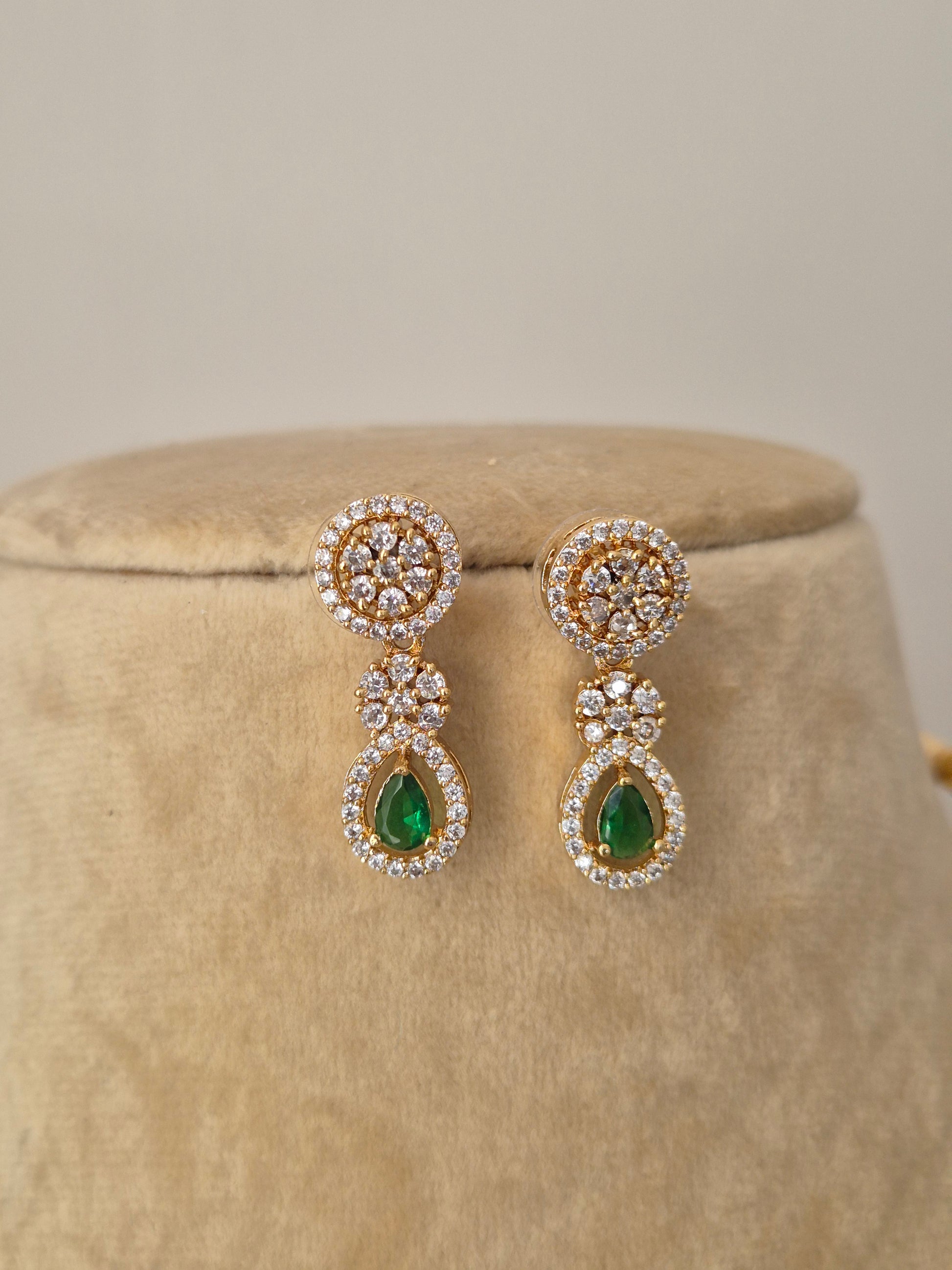 Handcrafted brass alloy necklace set with a polished gold finish, green synthetic stones, and clear American Diamond embellishments by naitri.in