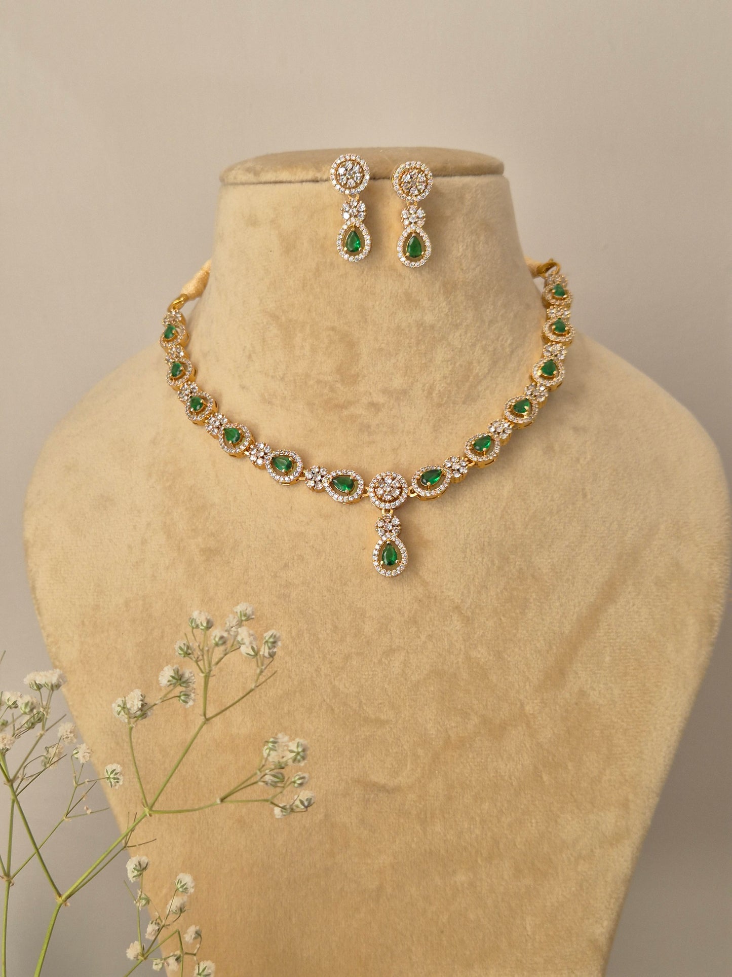 Gold-plated necklace with green teardrop stones and American Diamond accents, including matching drop earrings by naitri.in
