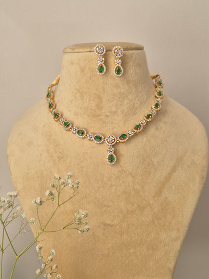 Gold-plated necklace with green teardrop stones and American Diamond accents, including matching drop earrings by naitri.in
