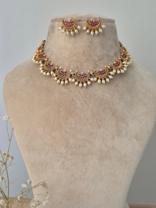 Gold jewelry design half-moon with small red stones in middle and pearls attached outside and same design earrings by naitri.in