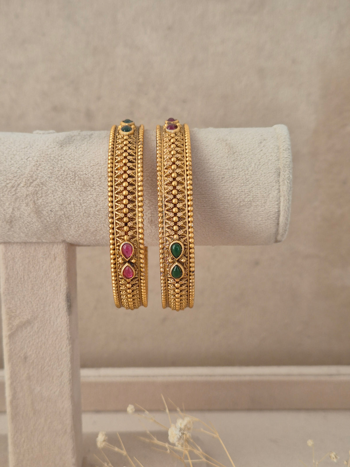 Set of 2 gold-plated bangles featuring a textured beaded mesh pattern, accented with teardrop ruby-red and emerald-green stones by naitri.in
