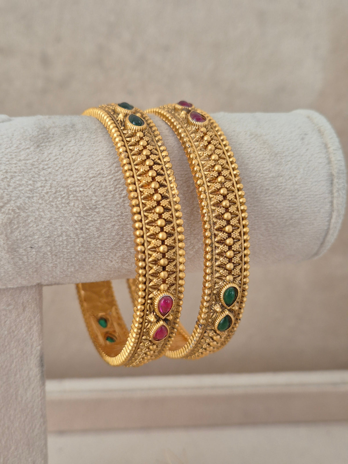 Elegant festive Indian gold-plated bangles with delicate relief work and vibrant gemstone highlights, perfect for weddings, Rakhi, and special occasions by naitri.in